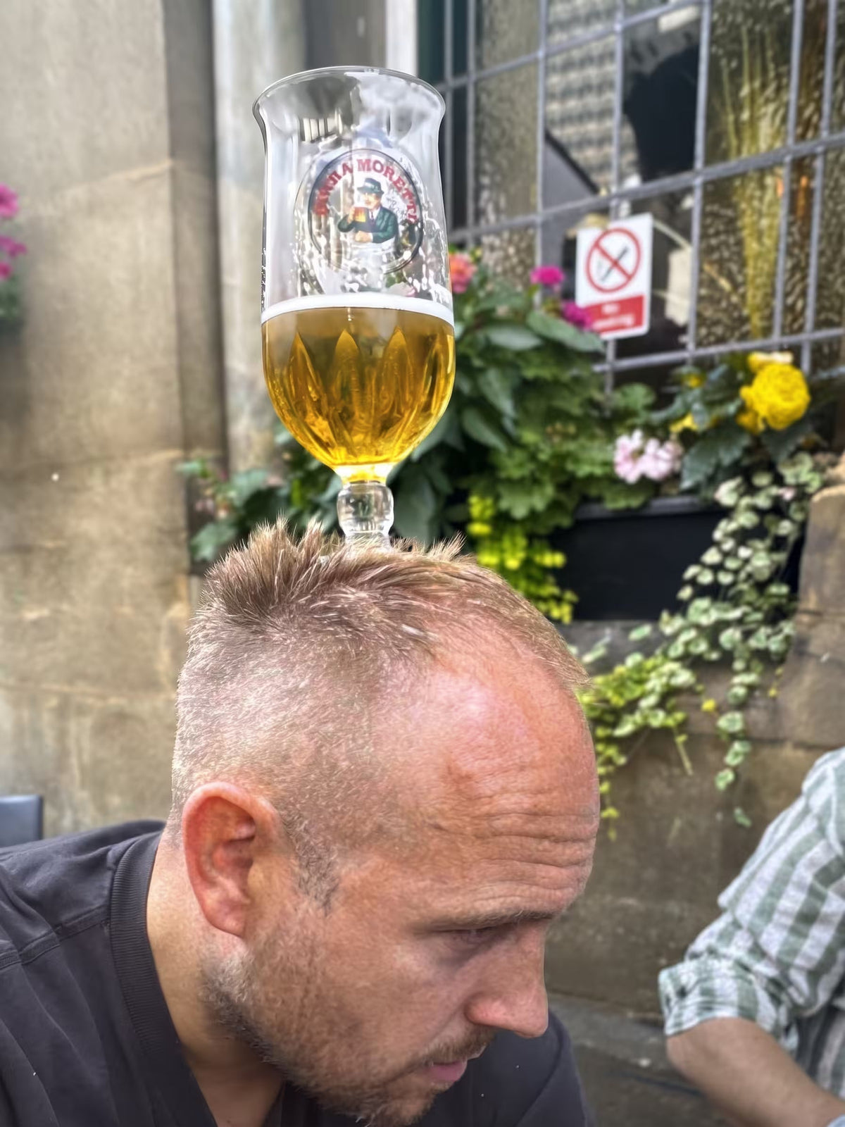 Man balancing a glass of beer on his head outside a pub for a party treasure hunt challenge