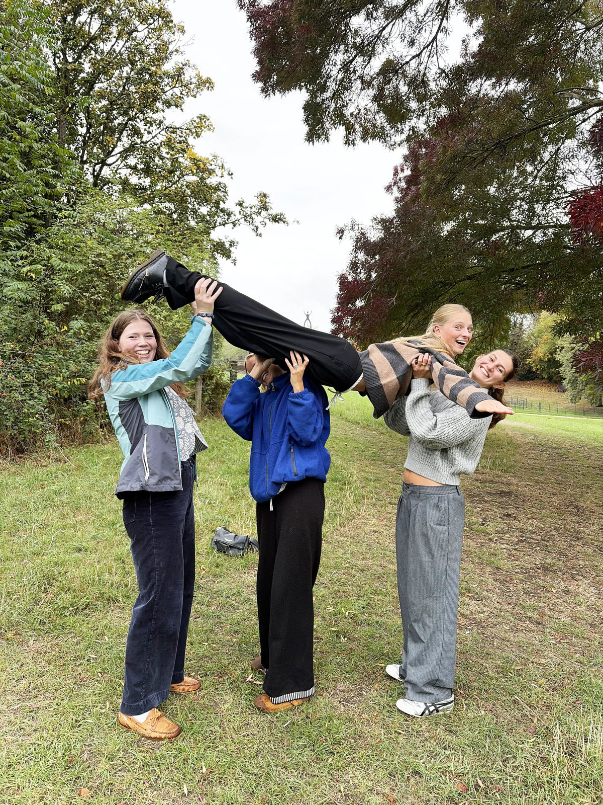 Friends lifting another friend into the air in a park for a party treasure hunt photo challenge