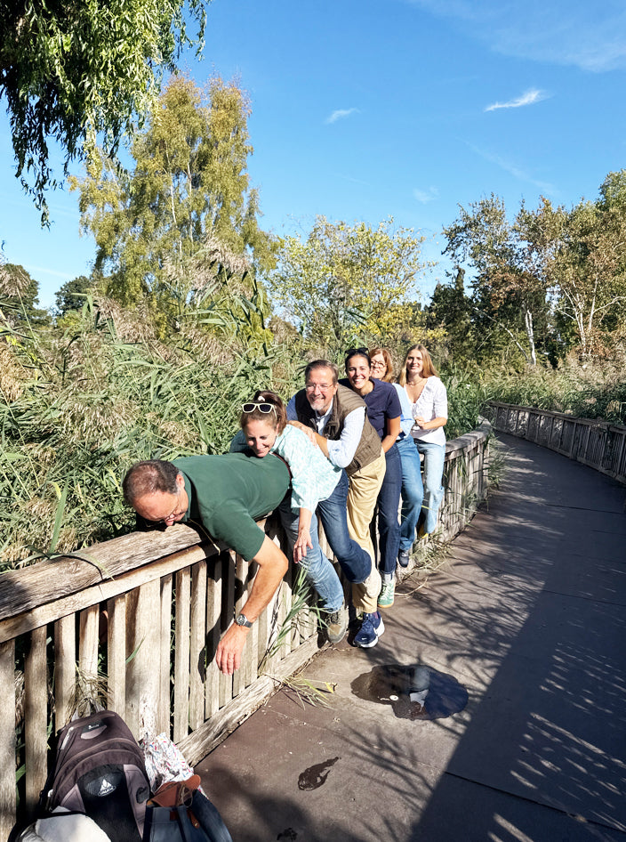 Group of friends lined up leaning over a wooden boardwalk rail for a treasure hunt photo challenge