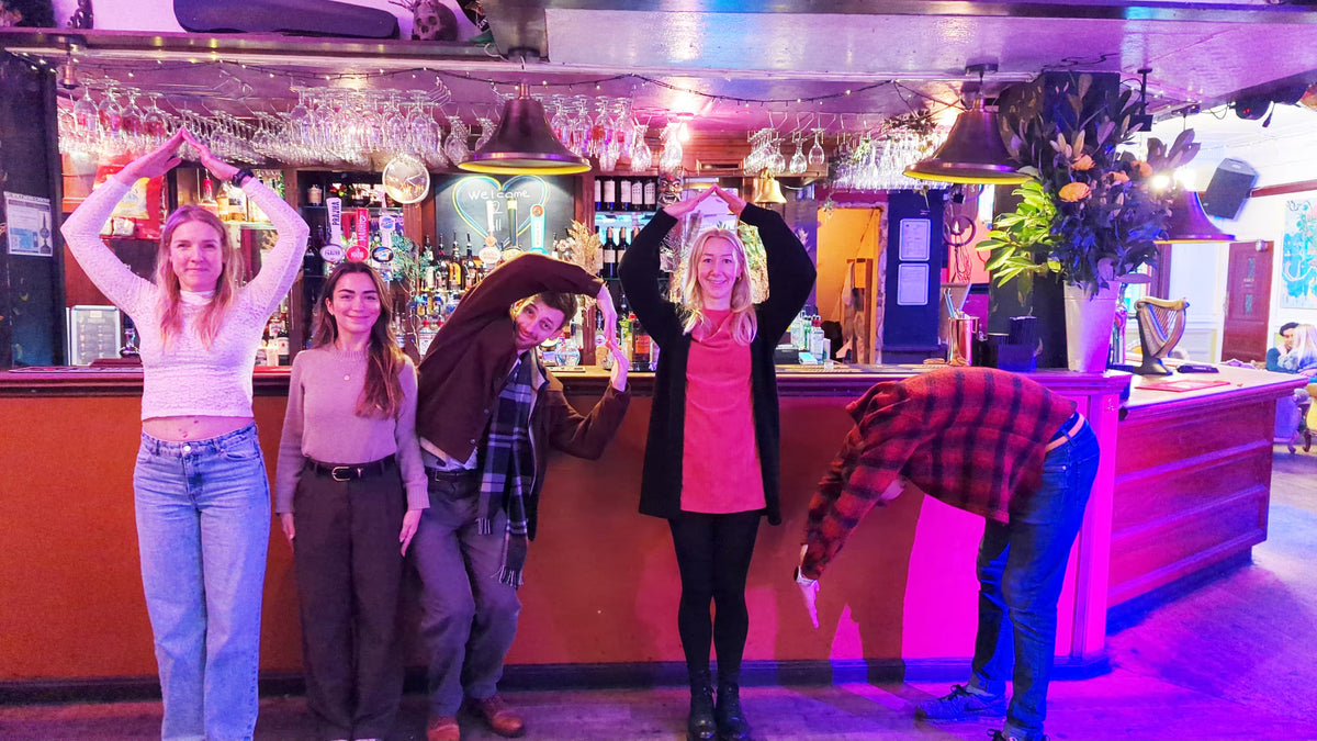 Group of friends striking poses in a colourful bar for a party treasure hunt photo challenge