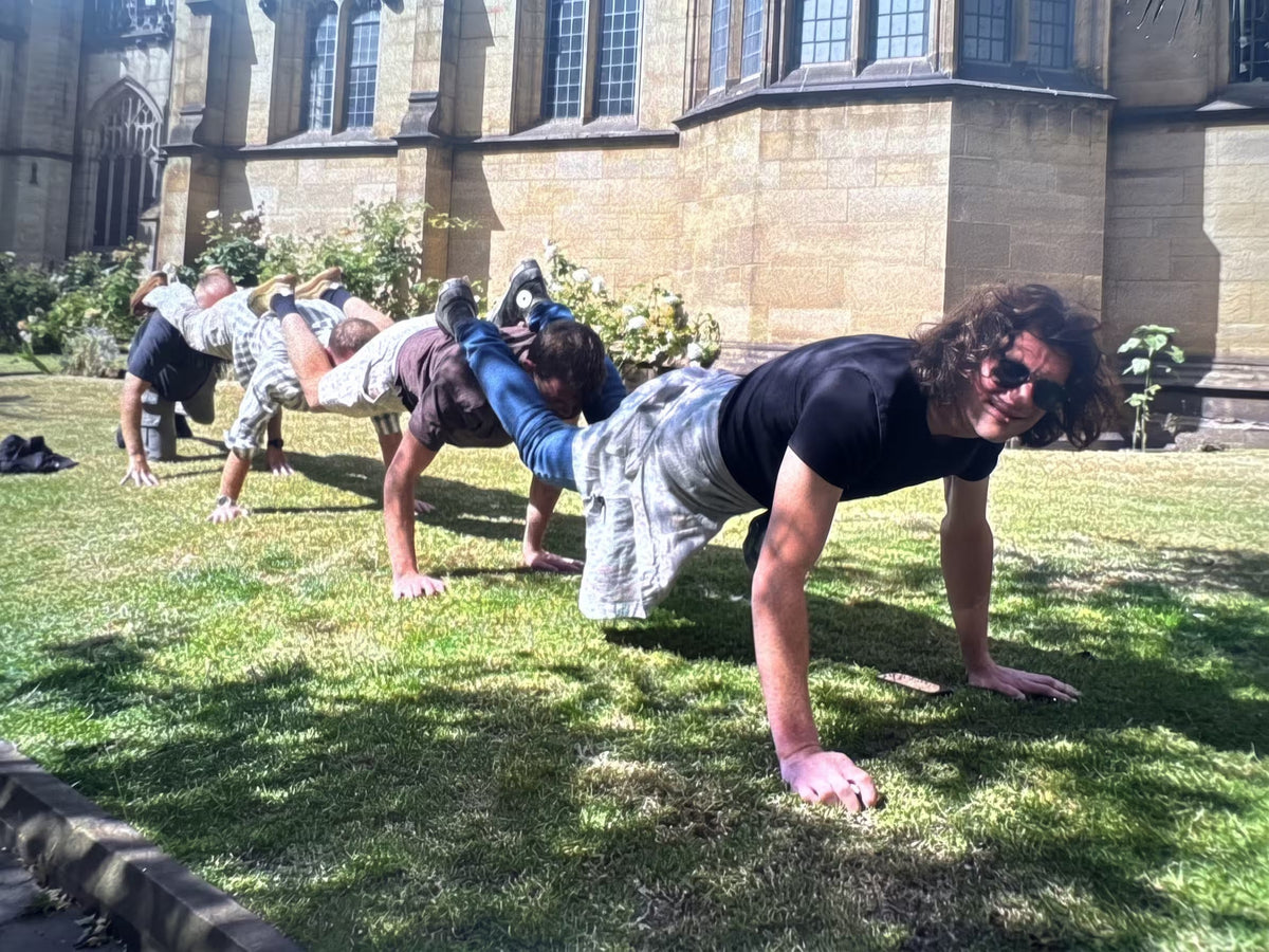 Friends forming a human caterpillar on the lawn outside a historic building for a treasure hunt photo challenge