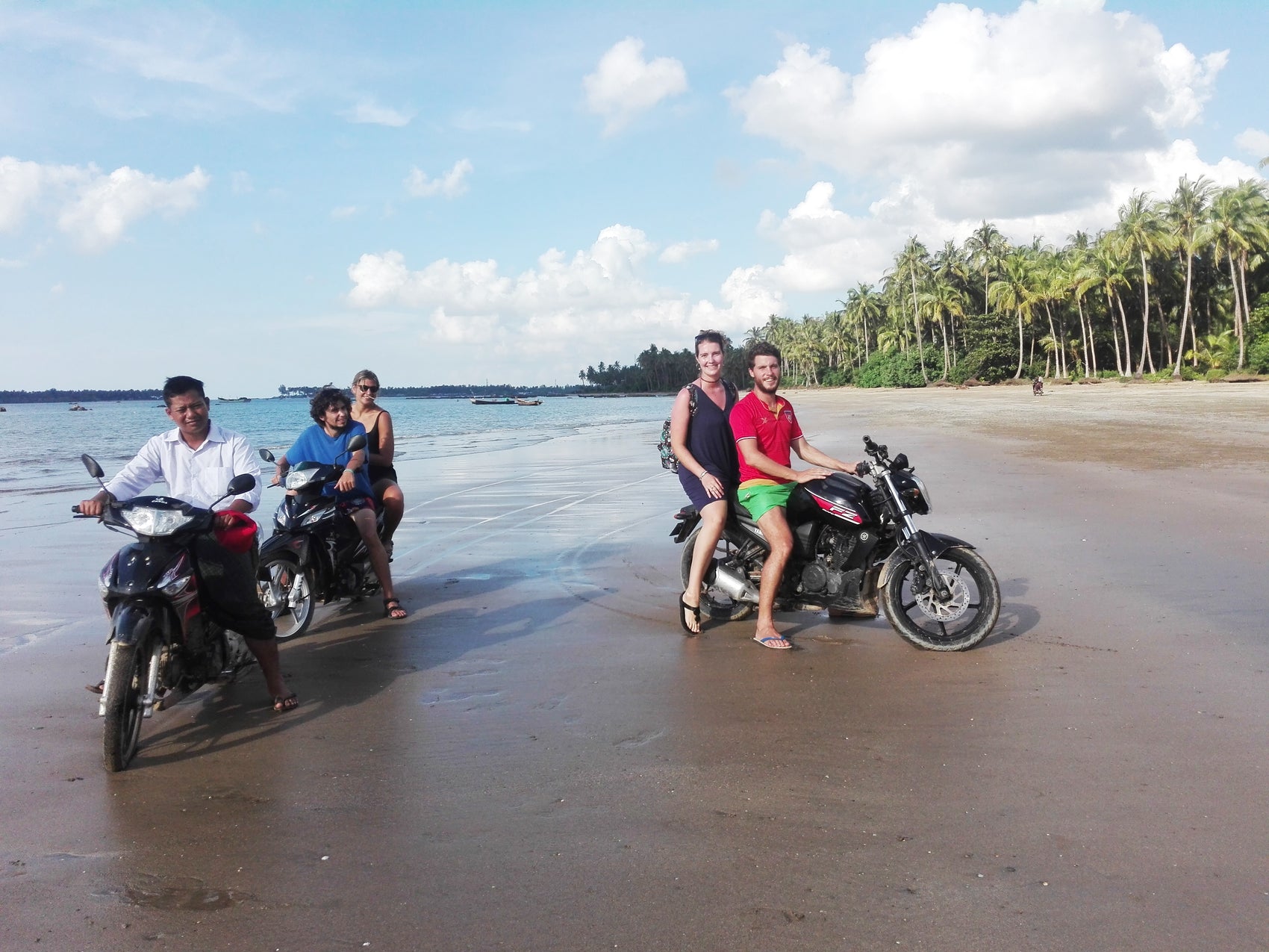 Bryn and Nick riding a motorbike with guests on the beach in Myanmar