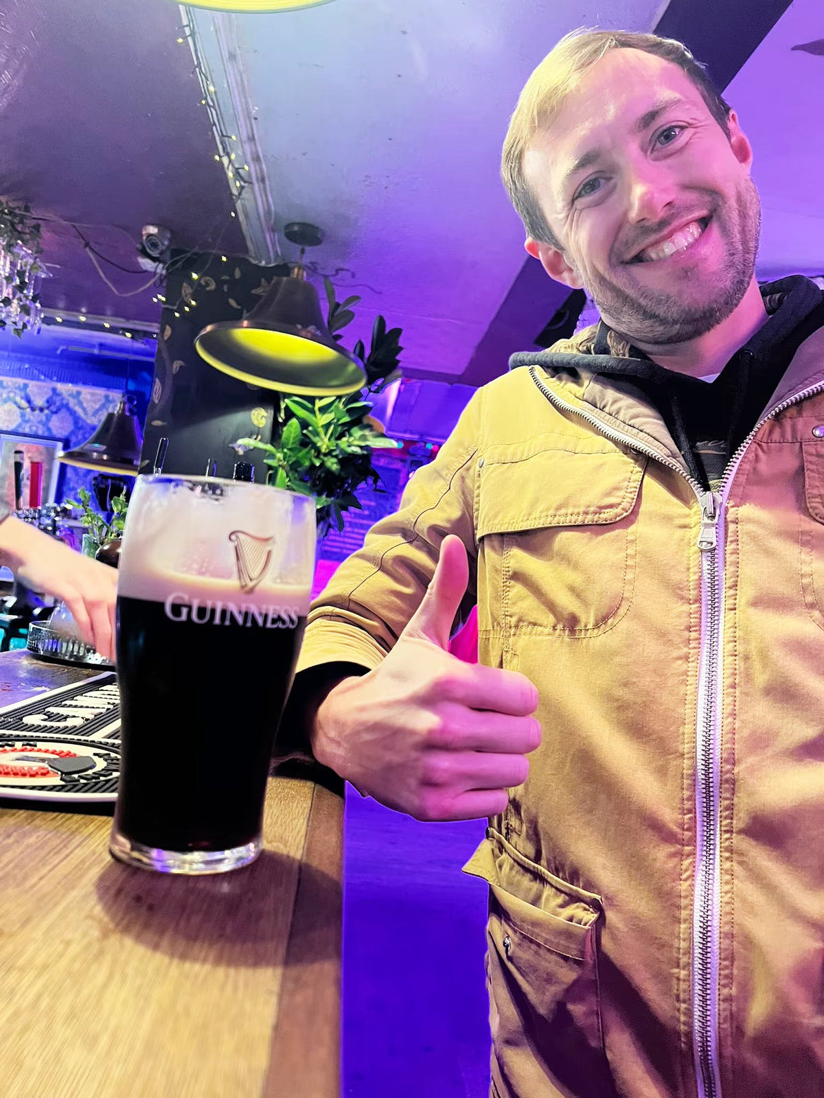 Smiling man giving a thumbs up next to a pint of Guinness at the bar during a treasure hunt pub stop